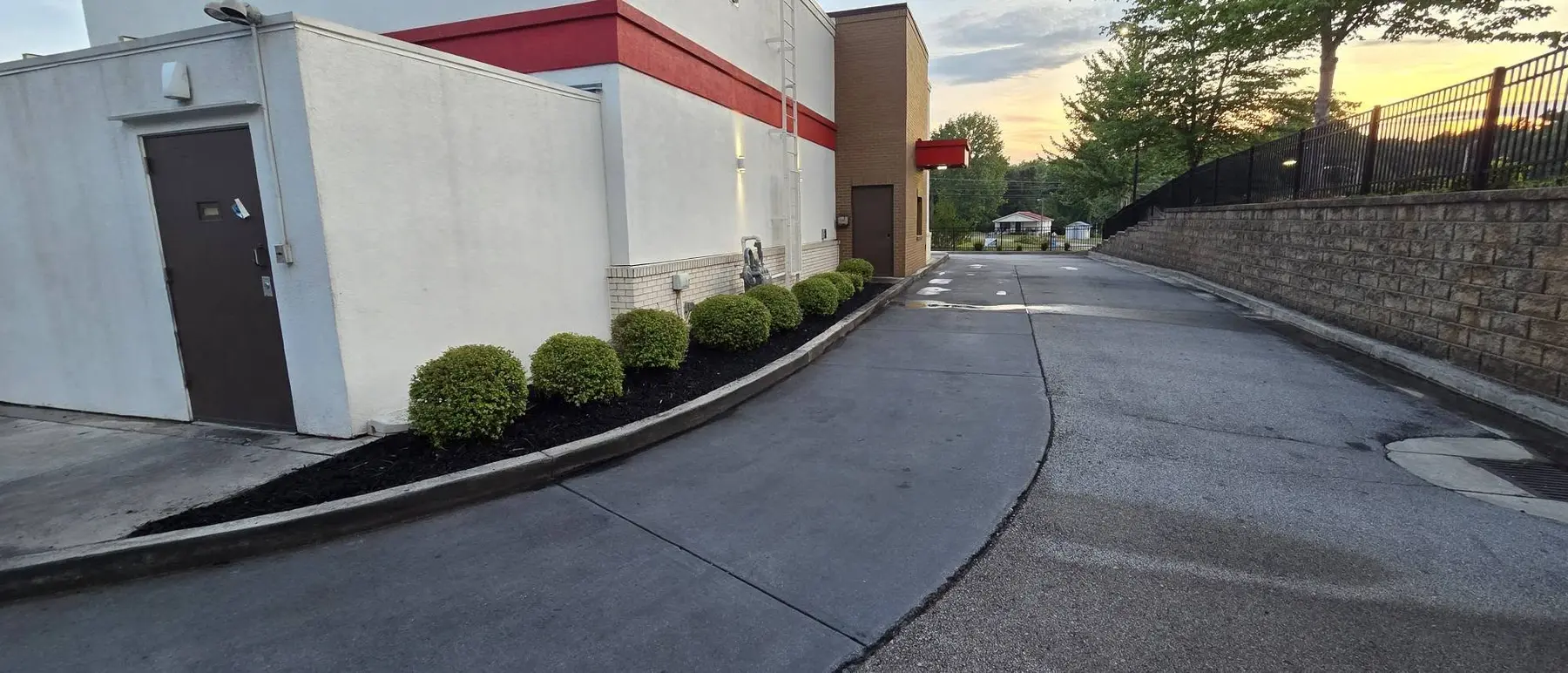 Neat foundation shrubs and refreshed dark mulch along the Arby’s drive lane