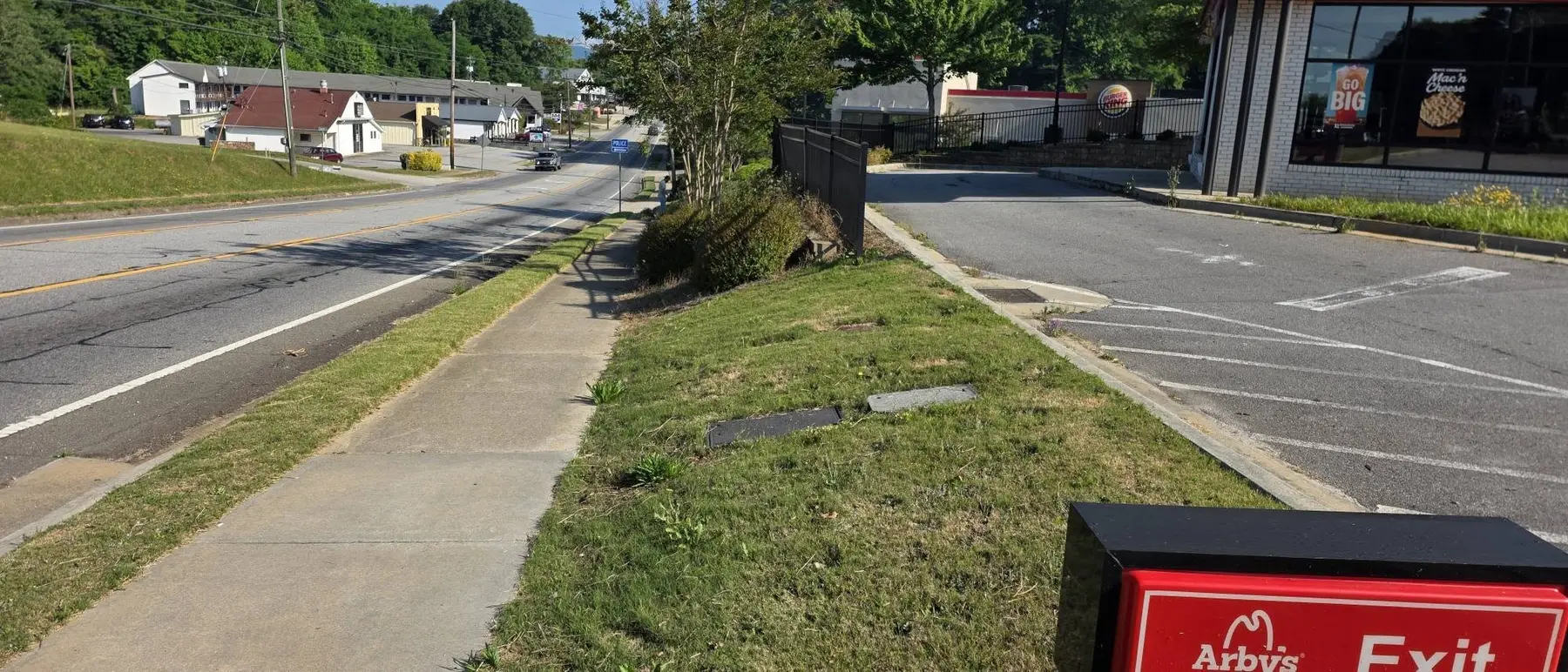 Roadside lawn and sidewalk area before cleanup and maintenance