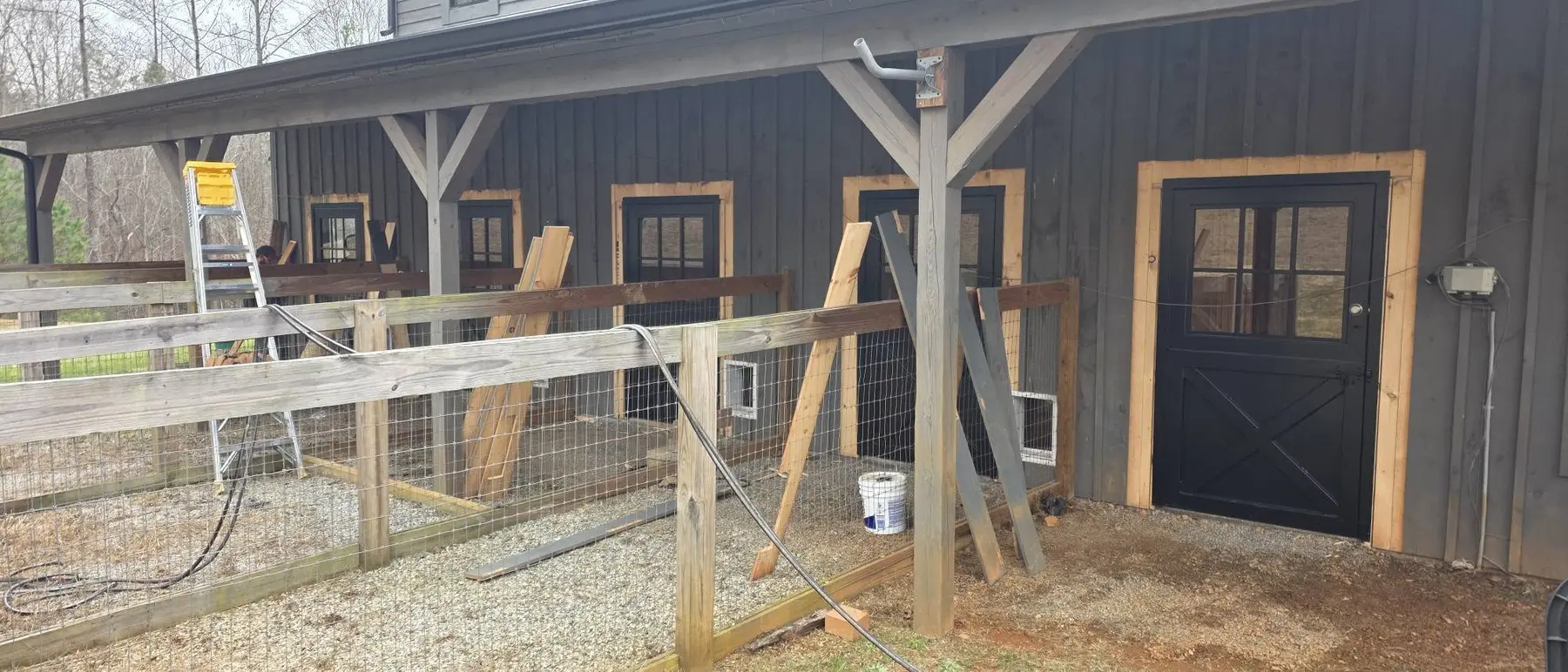 Row of newly installed black doors across the horse stable