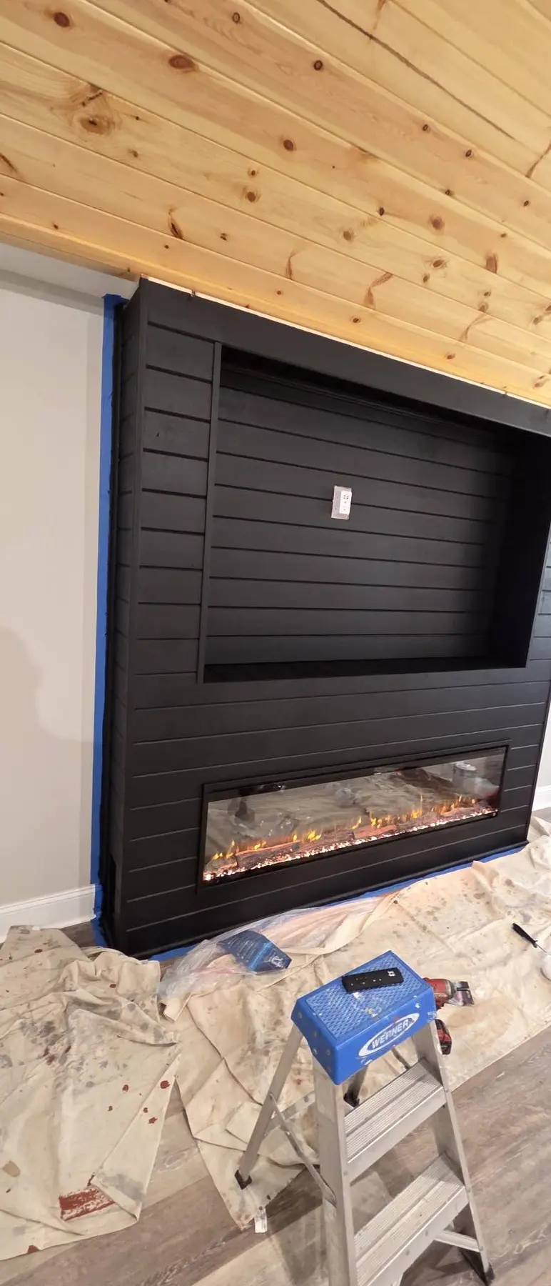 Black finished paneling and installed electric fireplace during construction